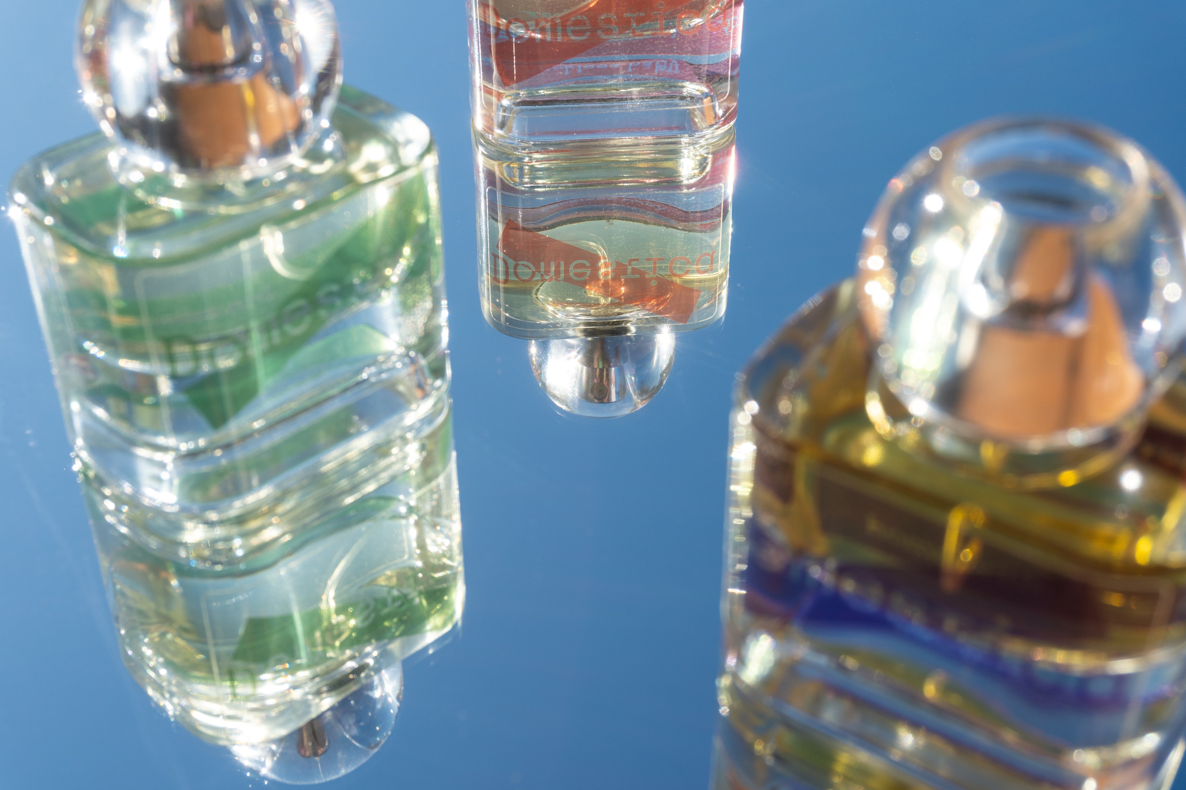 Three perfume bottles with visible labels against a blue background