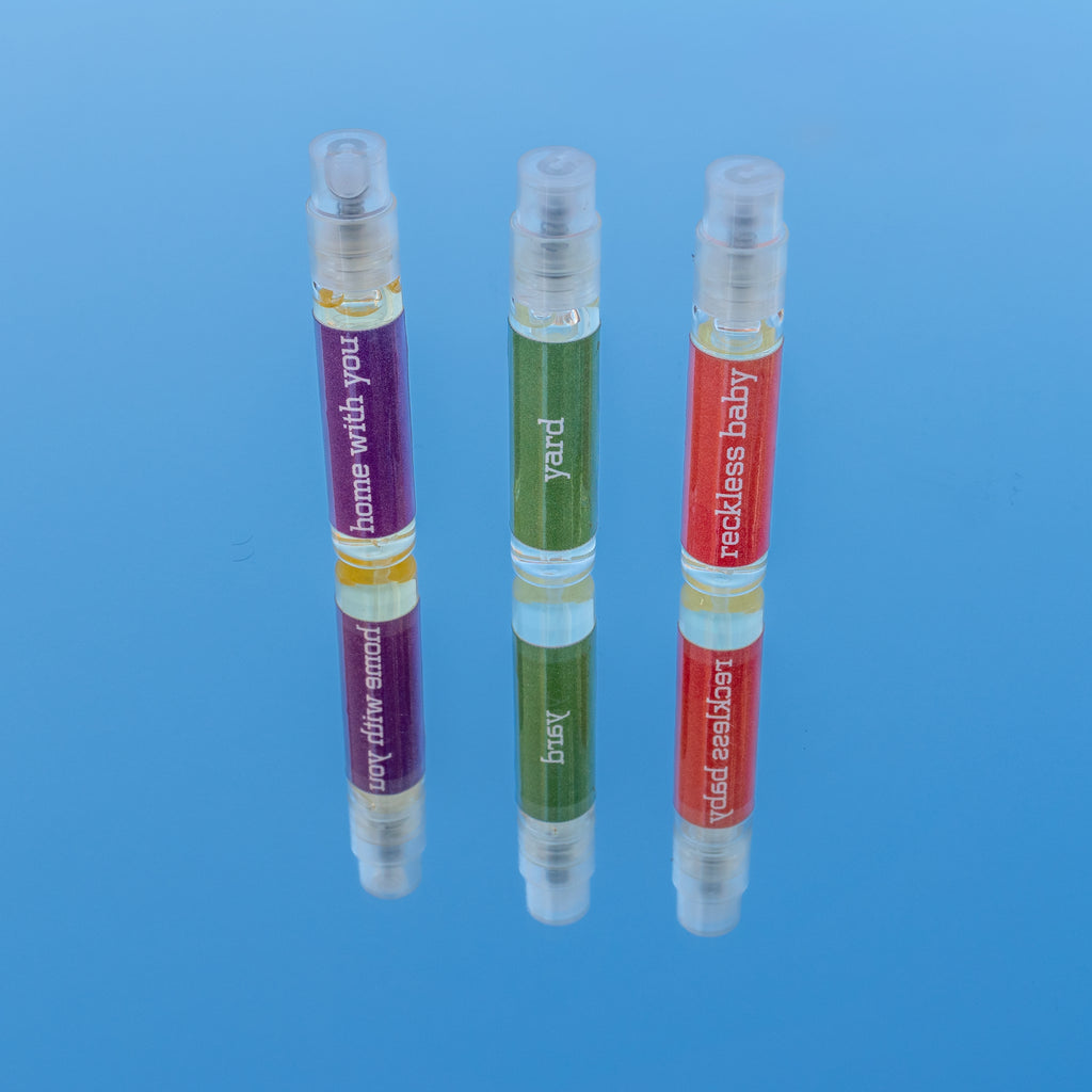 Three small perfume bottles with colorful labels on a blue background