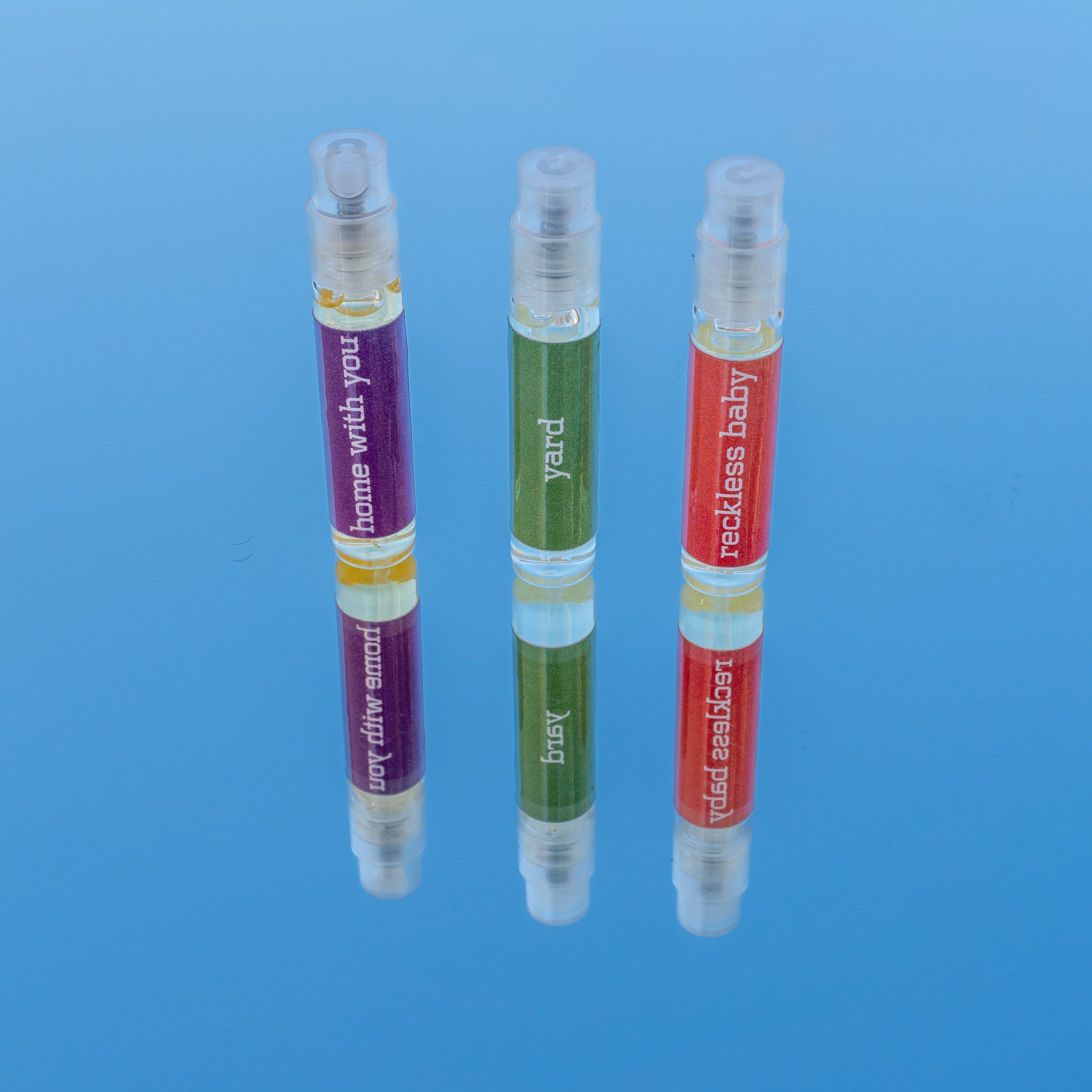 Three small perfume bottles with colorful labels on a blue background