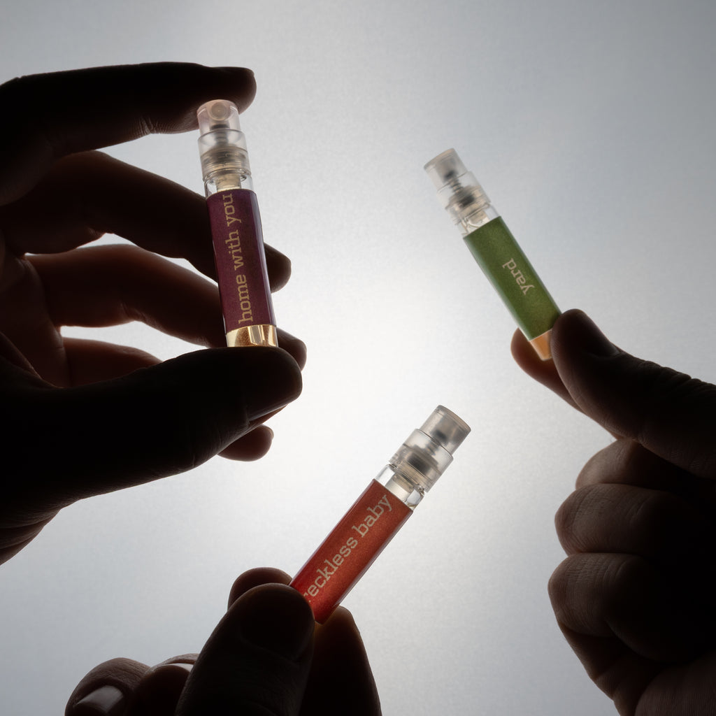 Three small bottles held by hands against a light background