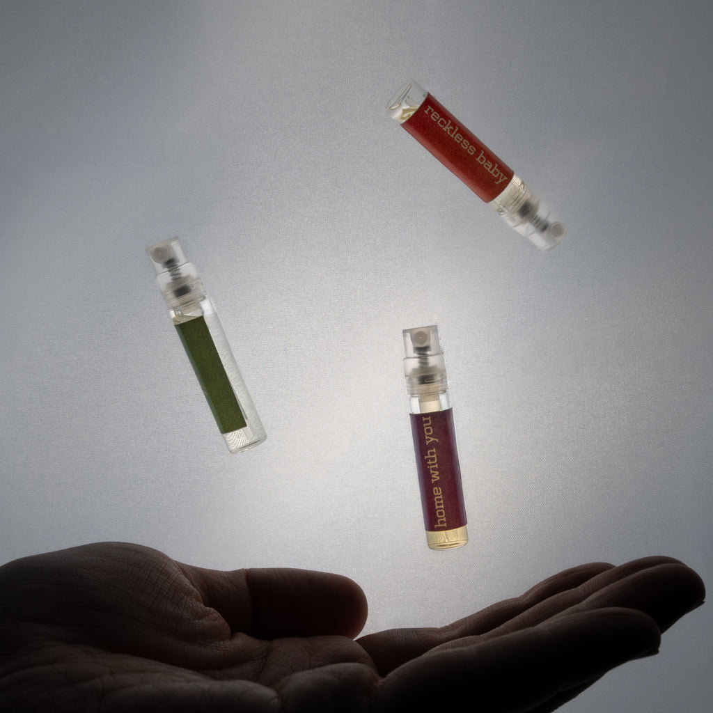 Three small glass bottles with colorful liquids levitating above a hand on a gray background