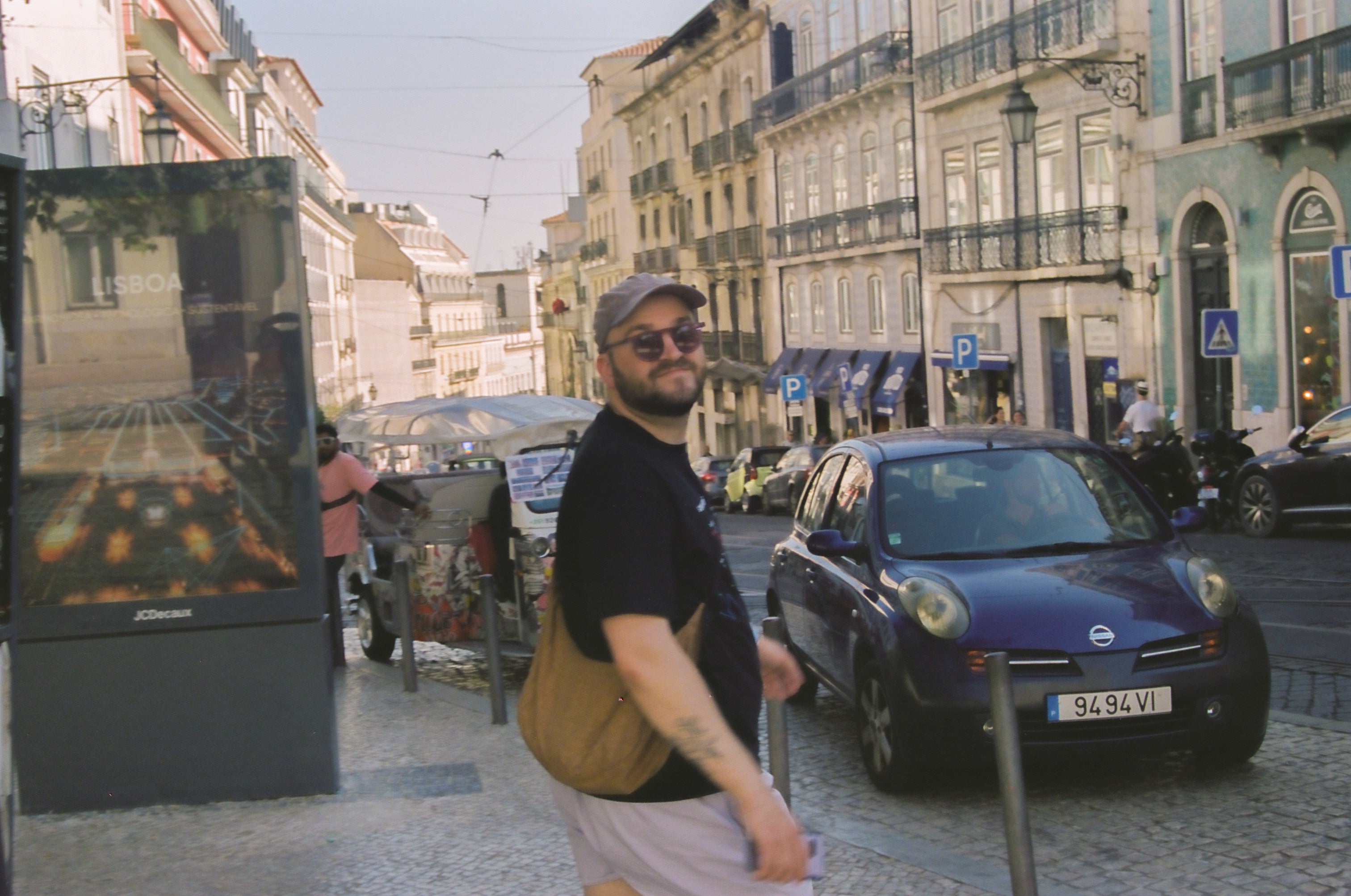 Man walking on a street with buildings and cars in the background